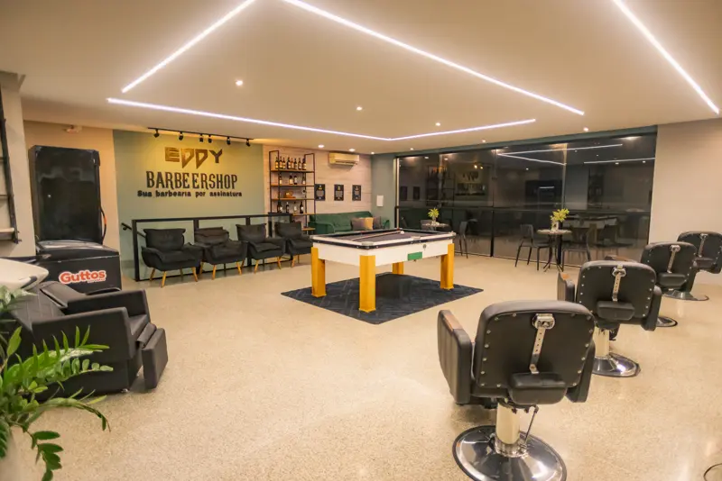 Salão principal com cadeiras de barbeiro e mesa de sinuca